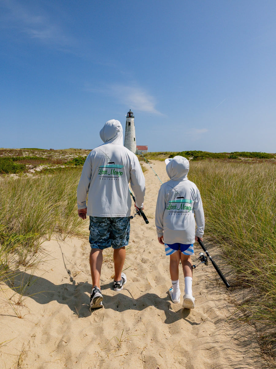 Two guests in Last Mango hoodies walking to the beach with rods